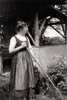 Munter in a dirndl, standing with a rake by the garden pavilion of the Murnau house